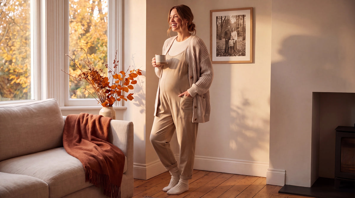 A woman wearing our tan oversized jumpsuit smiling in her living room